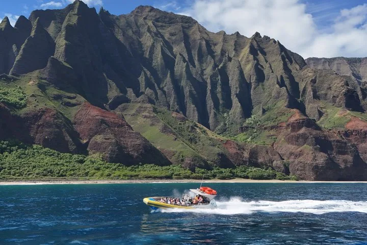 Super raft cruising beside the green cliffs on a Na Pali Coast boat tour from Eleele, Kauai
