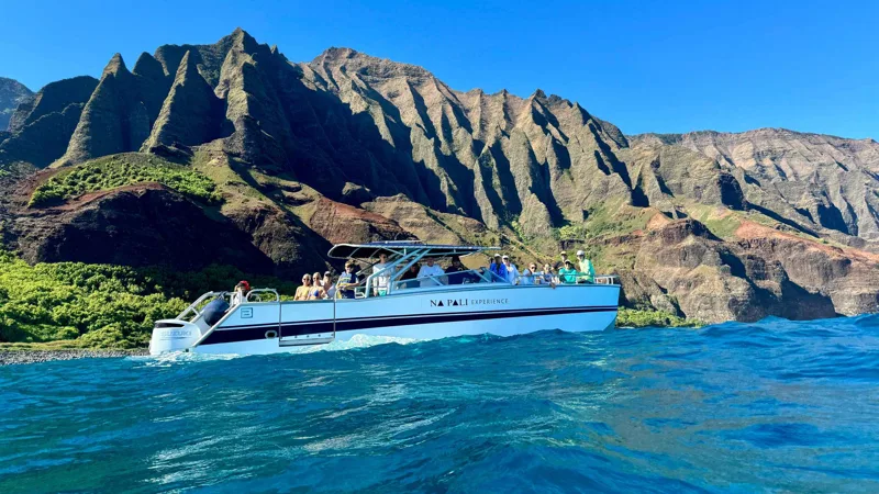 Power catamaran speeding along the sea cliffs on a Na Pali Coast boat tour from Kikiaola Small Boat Harbor, Kauai