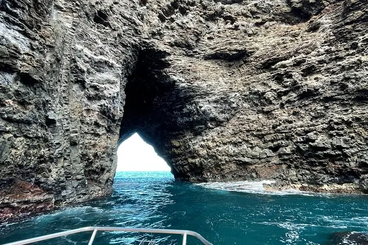 Catamaran under the green cliffs on a Na Pali Coast boat tour on the Amelia K, Kauai