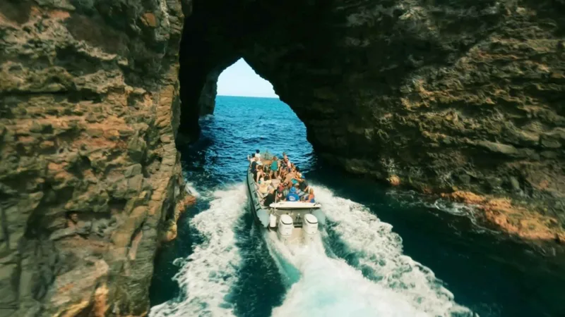 Zodiac rigid-hull raft at the mouth of a sea cave on a Na Pali Coast boat tour from Waimea, Kauai